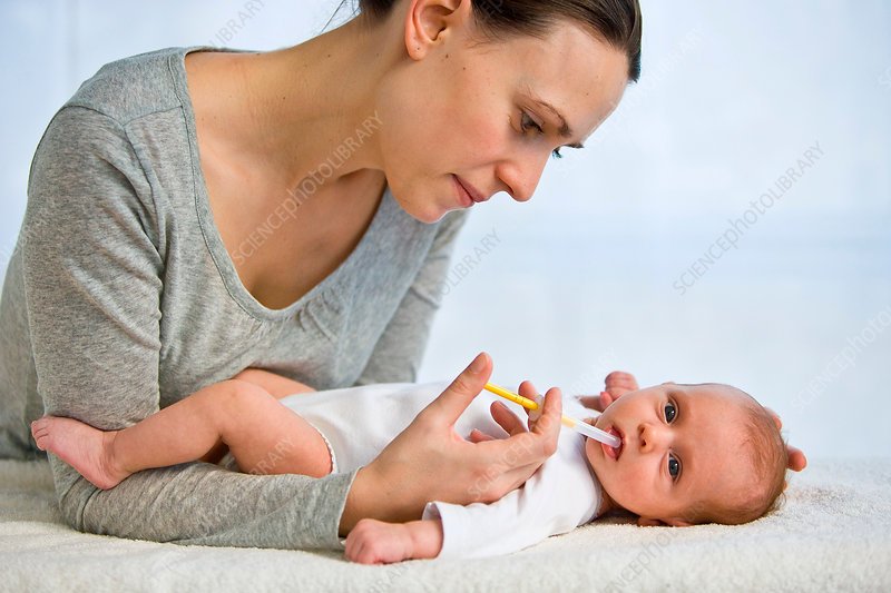 Mother giving vitamin D to baby