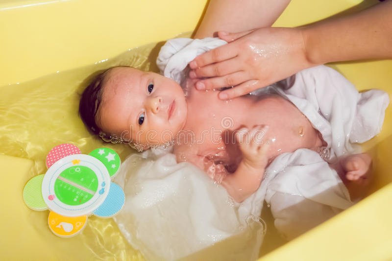 Newborn baby taking a bath stock image. Image of adorable